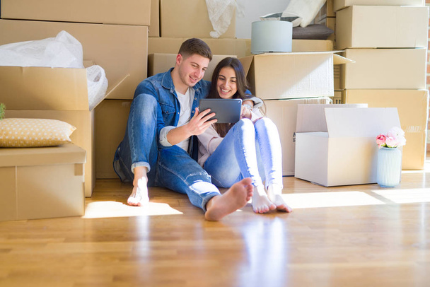 Молодая пара, сидящая на полу нового дома вокруг картона
  - Фото, изображение