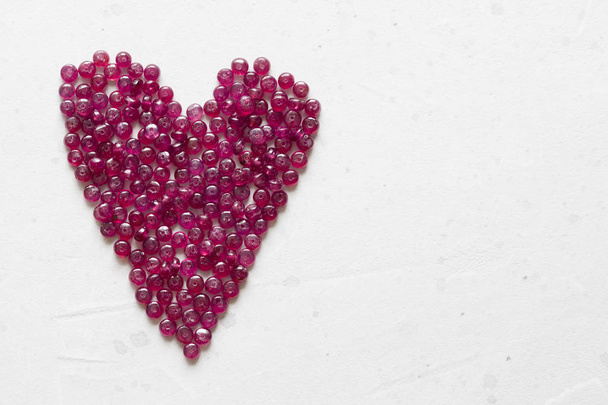 Рубиновые камни лежат на белом столе в форме сердца. Natura
 - Фото, изображение