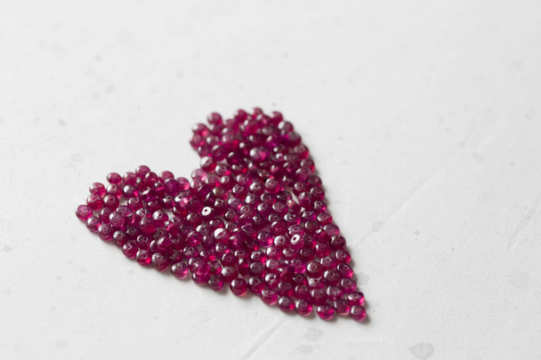 Рубиновые камни лежат на белом столе в форме сердца. Natura
 - Фото, изображение
