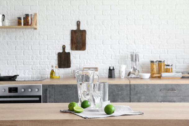 Gobelet et verres avec eau douce et citron vert sur la table dans la cuisine
 - Photo, image