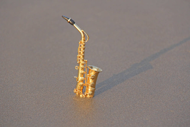 Il sassofono contralto dorato si erge sulla sabbia o sulla spiaggia. Mu
 - Foto, immagini