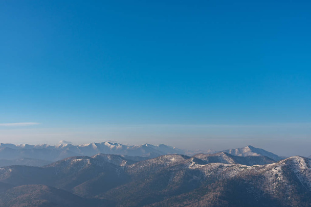 Panoramablick auf wunderschöne Berglandschaft, schneebedeckte Berggipfel mit Wald vor dunkelblauem Himmel im Frühling sonniger Tag - Foto, Bild