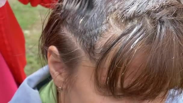 femme appliquant de la teinture capillaire sur sa tête avec un pinceau
 - Séquence, vidéo