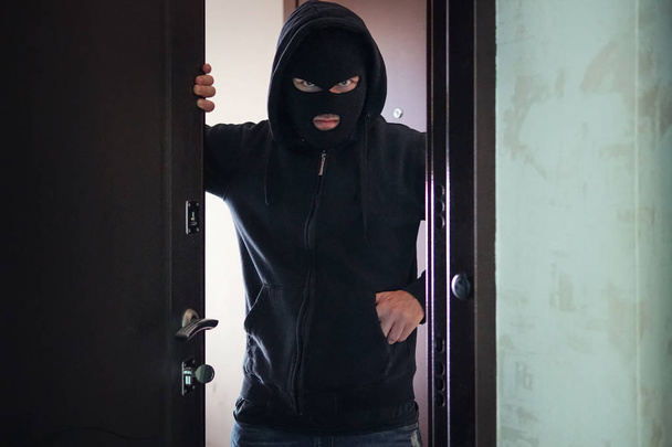 ロブに対する邪悪な脅迫が 私的所有権に侵入したアパートに押し入るマニアックが家に入った。犯罪と暴力の概念銃やナイフをポケットに入れて見知らぬ人への扉を開く - 写真・画像