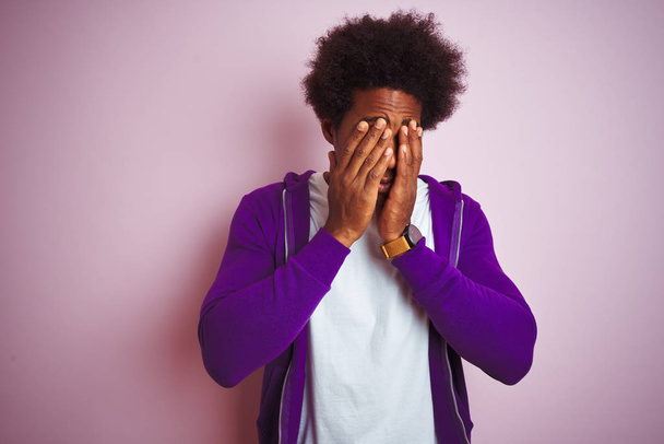 Hombre afroamericano joven con sudadera púrpura de pie sobre fondo rosa aislado frotando los ojos para la fatiga y el dolor de cabeza, la expresión somnolienta y cansada. Problema de visión
 - Foto, imagen