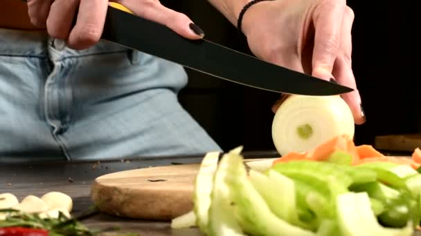 Close-up of female cook hands slicing onions on a wooden cutting board next to sliced vegetables. The concept of vegetarianism - Footage, Video