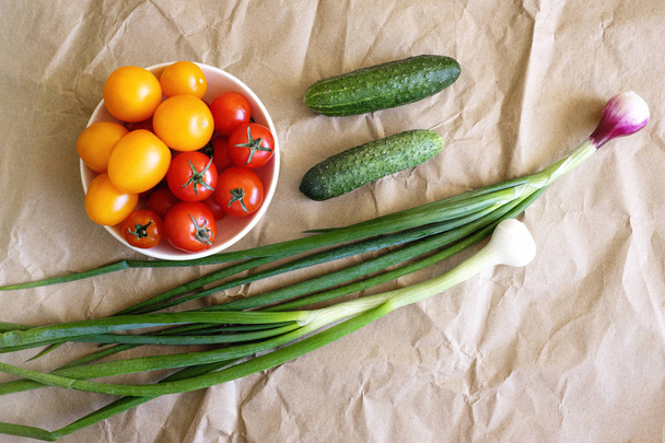 Świeże warzywa do sałatek na stole kuchennym: cebula, pomidory wiśniowe i ogórek  - Zdjęcie, obraz