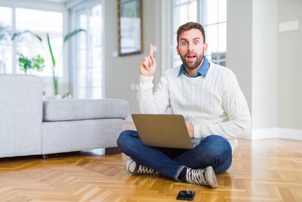 Przystojny mężczyzna noszenie pracy za pomocą komputera laptop wskazując palec w górę z sukcesem pomysł. Exited i szczęśliwy. Numer jeden. - Zdjęcie, obraz
