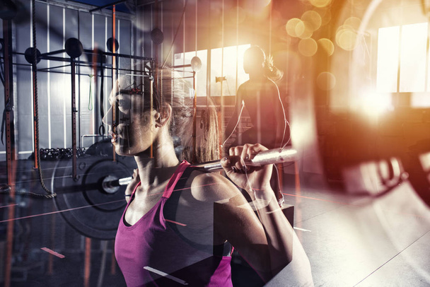 Athletic girl works out at the gym with a barbell. Female, healthy. Double exposure - Фото, изображение