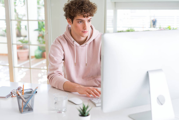 Young student man using computer with a confident expression on smart face thinking serious - Photo, Image