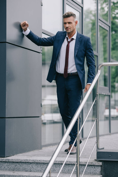 selective focus of displeased man in formal wear standing near building  - Fotó, kép