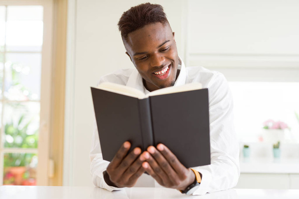 Joven hombre africano leyendo un libro, estudiando para univeristy sonriendo confiado
 - Foto, imagen