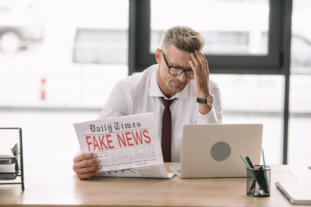 zdenerwowany biznesmen w okularach trzyma gazety z fałszywymi wiadomościami  - Zdjęcie, obraz
