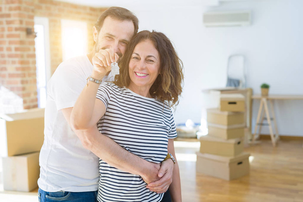 中年のシニアロマンチックなカップルは、新しい家に引っ越すために幸せに微笑む家の鍵を保持し、示しています - 写真・画像