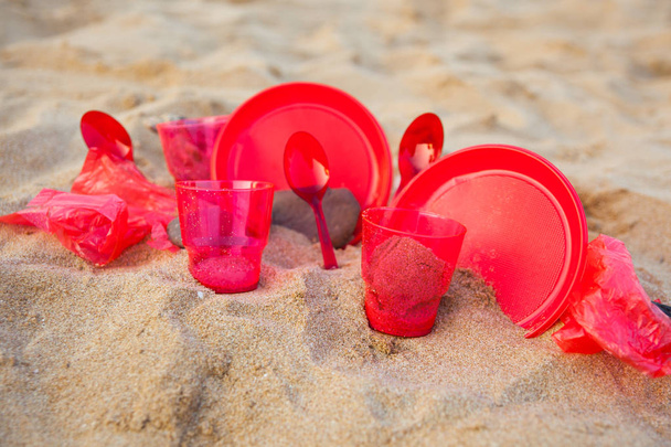 close up view of red plastic dishware on sandy beach - Фото, зображення