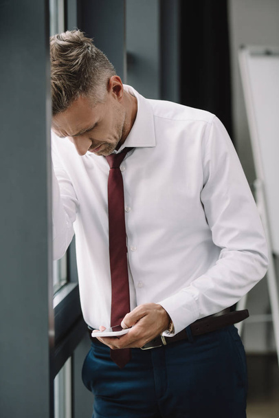 upset businessman standing in suit and using smartphone  - Zdjęcie, obraz
