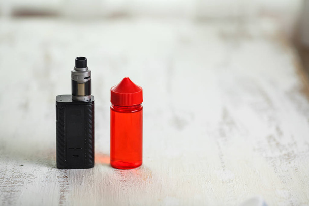 Vape objects. Electronic cigarette and jar with e-liquid on a light wooden table. - Photo, image