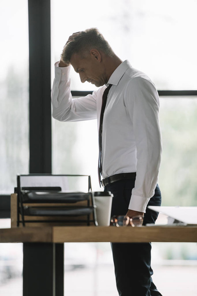 вибірковий фокус засмученого бізнесмена торкається голови біля столу в офісі
  - Фото, зображення