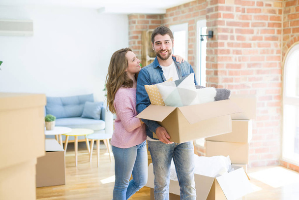 Jovem casal bonito muito feliz juntos segurando caixas de papelão se movendo para uma nova casa
 - Foto, Imagem