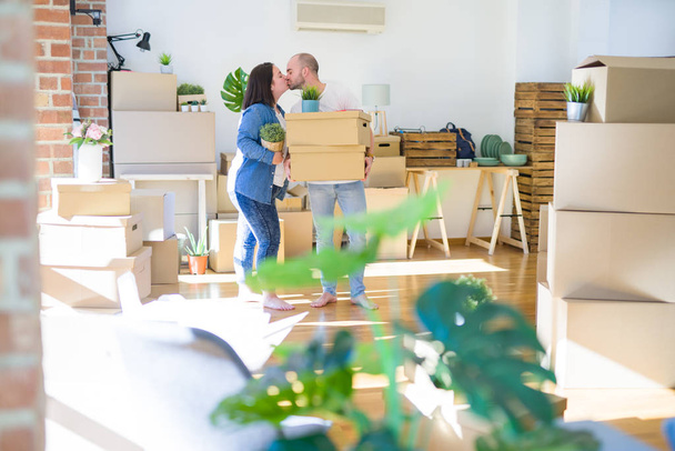 Jeune couple déménageant dans une nouvelle maison, souriant heureux tenant boîtes en carton
 - Photo, image