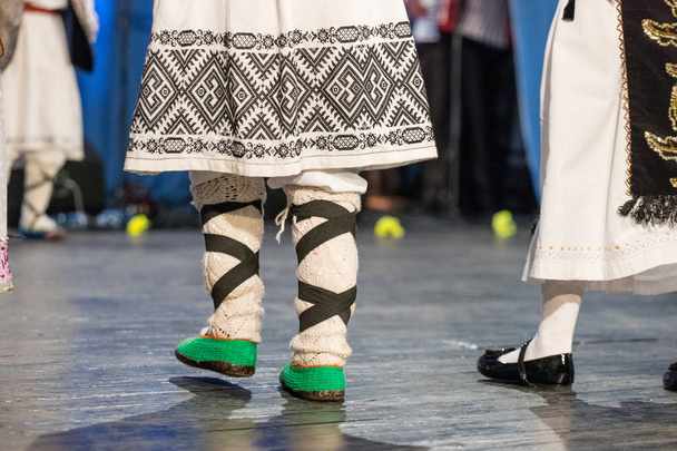 Primer plano de las piernas de los jóvenes bailarines rumanos realizan una danza folclórica en traje folclórico tradicional. Folklore de Rumania
 - Foto, Imagen