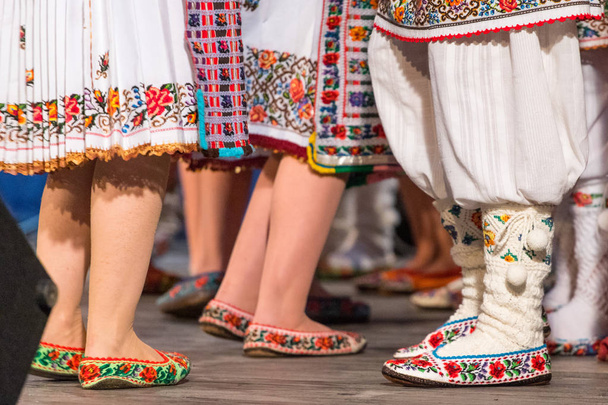Blízko nohou mladých rumunských tanečníků se v tradičním folklorním kostýmu provádí folkový tanec. Folklór Rumunska - Fotografie, Obrázek