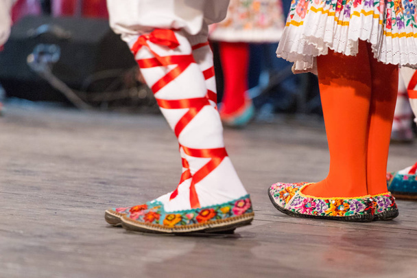 A fiatal román táncosok lábai közelről néptáncot hajtanak végre hagyományos népviseletben. Romániai folklór - Fotó, kép