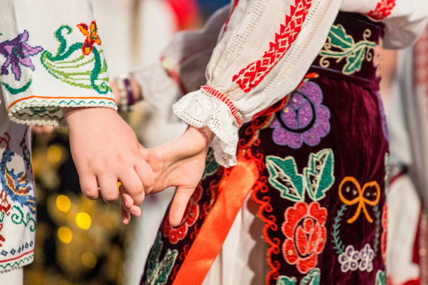 Крупным планом руки молодых румынских танцоров исполняют народный танец в традиционном фольклорном костюме. Фольклор Румынии
 - Фото, изображение