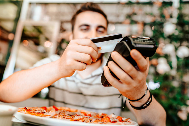 Smiling man paying at restaurant using smartphone. mobile paying technology with contactless credit card - Φωτογραφία, εικόνα