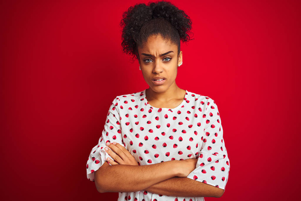 Femme afro-américaine portant robe blanche de mode debout sur fond rouge isolé sceptique et nerveux, expression désapprobatrice sur le visage avec les bras croisés. Personne négative
. - Photo, image