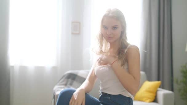 Portrait of happy young lady looking at camera and smiling in cozy living room - Záběry, video