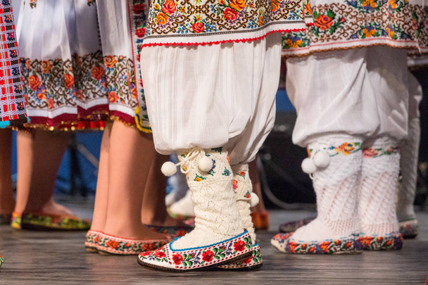 Primo piano delle gambe dei giovani ballerini rumeni eseguire una danza popolare in costume folcloristico tradizionale. Folclore di Romania
 - Foto, immagini