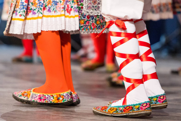 Gros plan des jambes de jeunes danseurs roumains exécutent une danse folklorique en costume folklorique traditionnel. Folklore de Roumanie
 - Photo, image