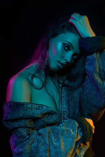 Fashion trendy portrait photo of a young beautiful attractive female girl model in trendy modern gel light in studio on a dark black background - Фото, зображення