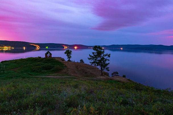 Beautiful long exposure landscape view of the mountain lake Turgoyak, Russia with purple sky and summer house on the hill in summer night - Photo, Image