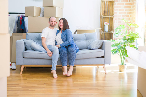 Młoda para w miłości relaks i przytulanie siedzi na kanapie w nowym domu, uśmiechając się bardzo szczęśliwy do przejścia do nowego mieszkania - Zdjęcie, obraz
