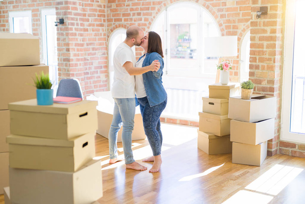 Mladí manželé tančí kolem lepenkových krabic v novém domě, oslavují usměvavou a šťastný nový dům - Fotografie, Obrázek