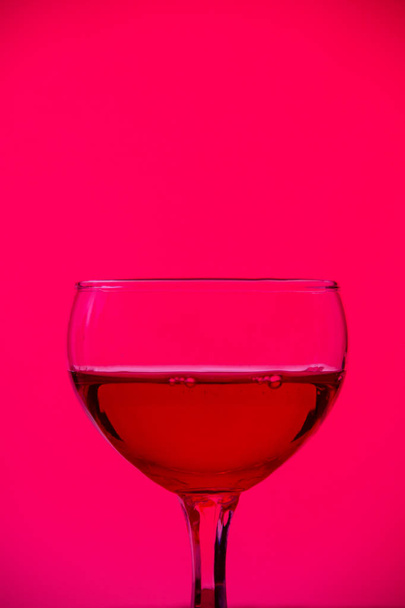 Glass goblet with drink on a bright pink background. - Photo, Image