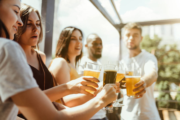 Young group of friends drinking beer and celebrating together - Fotoğraf, Görsel