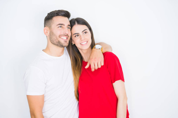 Young beautiful couple together over white isolated background looking away to side with smile on face, natural expression. Laughing confident. - Foto, immagini