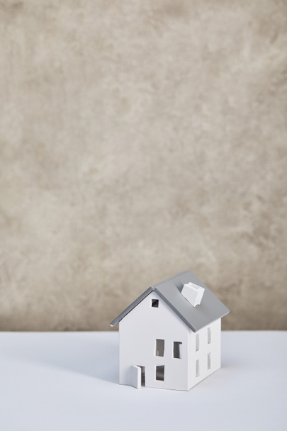 modelo de casa en mesa blanca cerca de pared texturizada gris, concepto de bienes raíces
 - Foto, Imagen