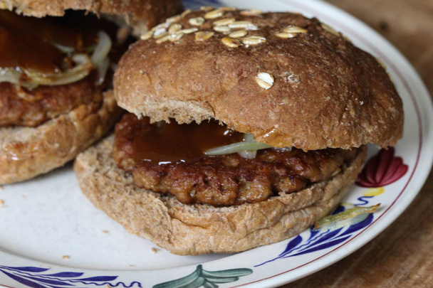 close-up zicht op verse vegetarische soja hamburger op plaat op houten achtergrond. De hamburger heeft gebakken uien en curry ketchup - Foto, afbeelding