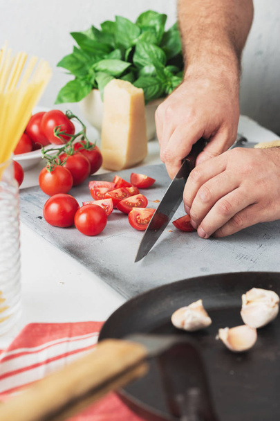 Chef cocinando pasta con tomates en la cocina casera
 - Foto, imagen