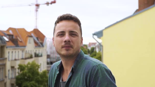 Portrait of a young man on a balcony in a big city - Felvétel, videó