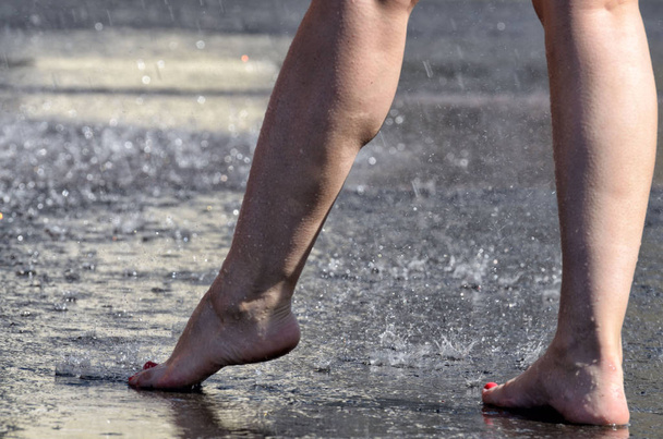 Marcher pieds nus sous la pluie à travers les flaques
. - Photo, image
