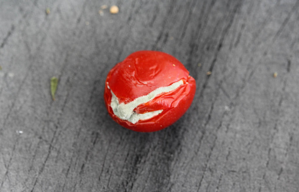 Tomate cerise pourrie sur fond de planche à découper noire
 - Photo, image