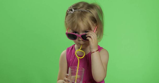 Счастливый четырехлетний ребенок в розовом платье пьет коктейль из молочного коктейля. Ключ хромы
 - Фото, изображение