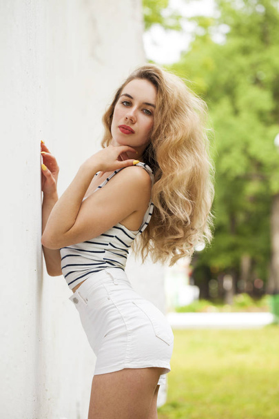 Portrait of a young beautiful blonde girl in white shorts - Foto, Imagem