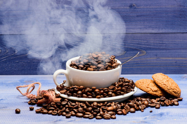焙煎穀物の程度。カップフルコーヒーブラウンロースト豆白い雲の煙青い木製の背景。カフェドリンクメニュー。新鮮な焙煎コーヒー豆。インスピレーションとエネルギーチャージのためのコーヒー - 写真・画像