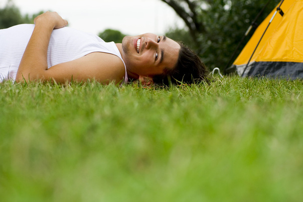 テントの近くに草に横たわっている男 - 写真・画像